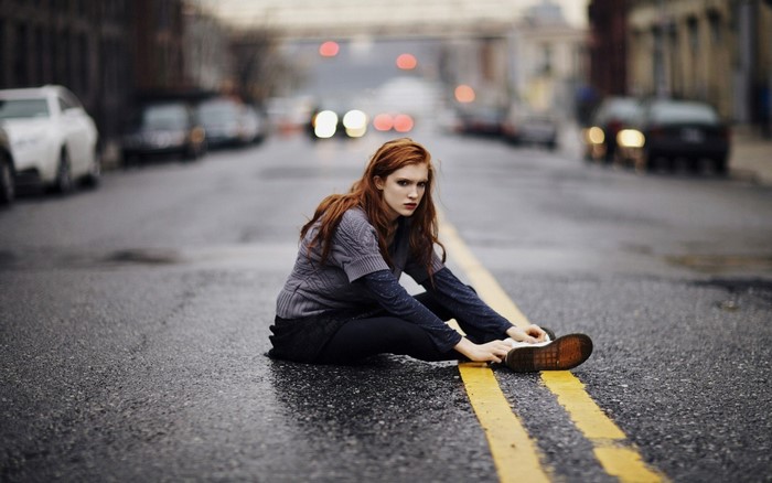 Redhead woman sitting on a city street