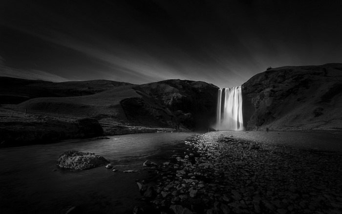 Monochrome waterfall landscape with river and rocky shore