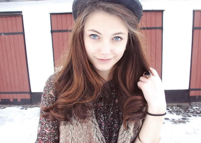 Woman with long brown hair and blue eyes wearing a fur vest