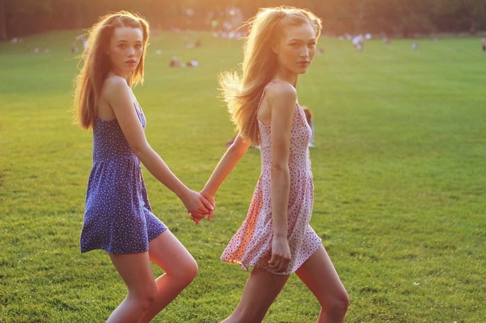 Two Girls Holding Hands in Sunny Meadow
