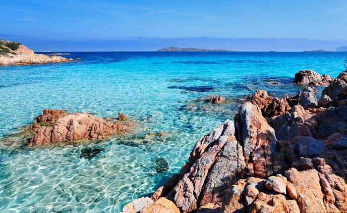 Turquoise sea and rocky shore with islands in the distance