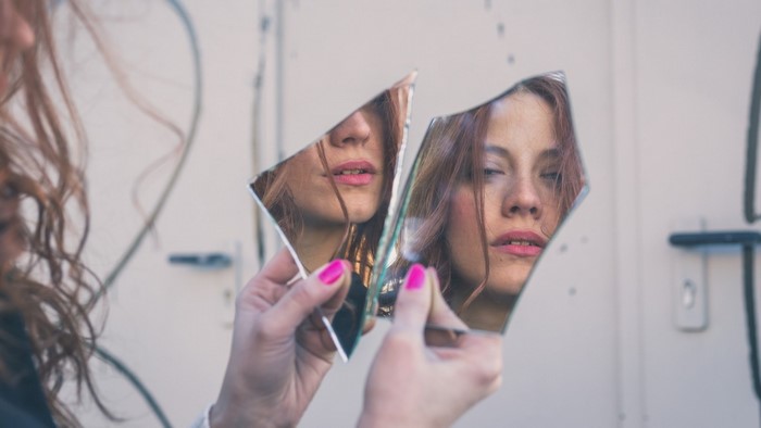 Woman holding broken mirror reflecting her face