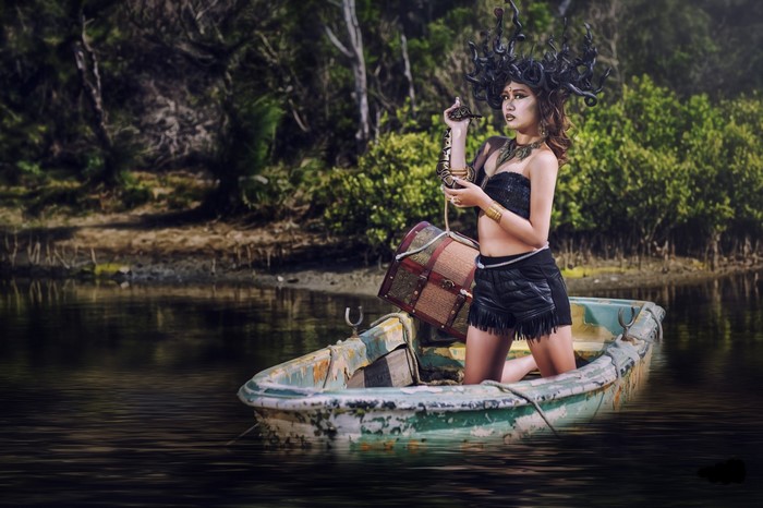 Woman dressed as Medusa with snake in a boat