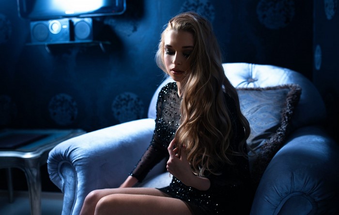 Woman in sequined dress sitting in a blue armchair