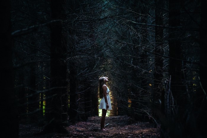 Woman in white dress in dark forest
