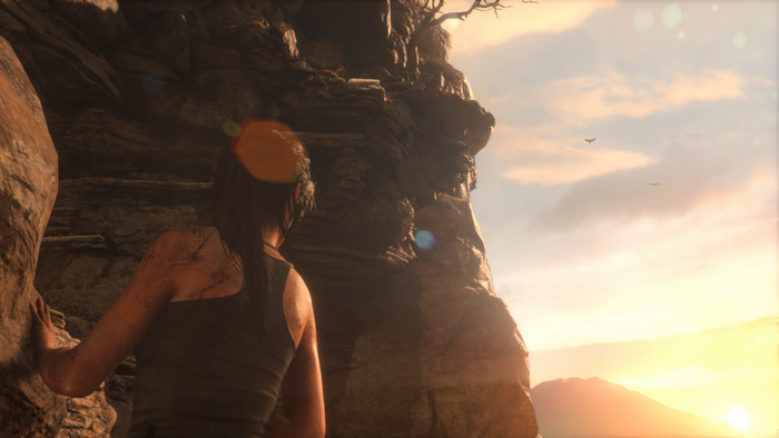 Lara Croft from Tomb Raider climbing a cliff at sunset