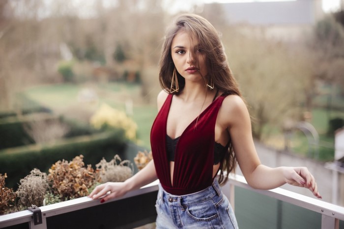 Woman in red velvet bodysuit and denim shorts on balcony