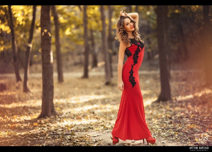 Woman in red dress posing in autumn forest