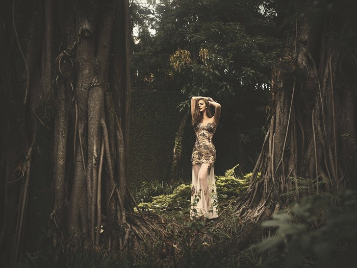 Woman in a dress standing between large trees