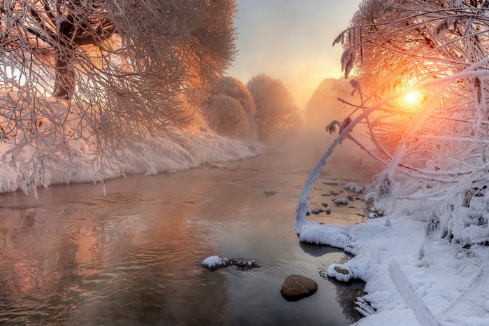 Winter river at sunrise with frost and mist