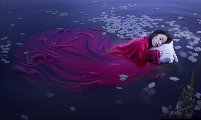 Woman sleeping on a pillow in water with lily pads