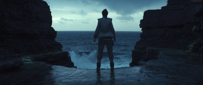 Rey from Star Wars: The Last Jedi on a rocky shore