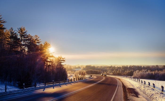 Winter road at sunrise with sun flare