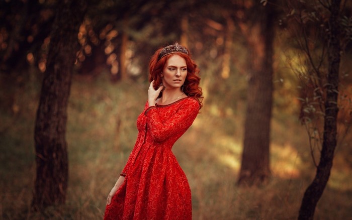 Redhead woman in red dress with crown in forest