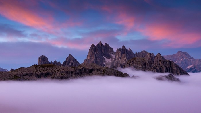 Mountain range above clouds at sunset