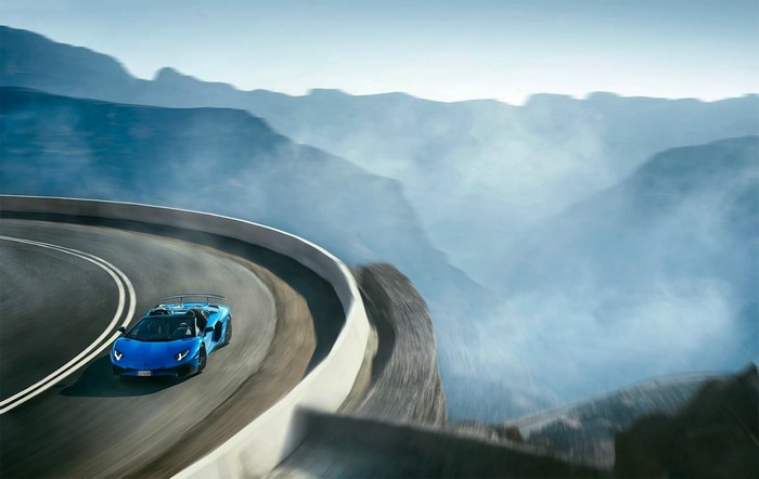 Blue Lamborghini Aventador driving on a mountain road