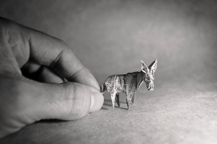 Origami donkey made of newspaper held by a hand