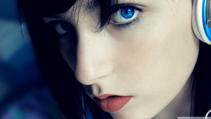 Close-up portrait of a young woman with blue eyes and headphones