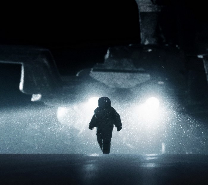 Astronaut walking towards bright lights of a spacecraft
