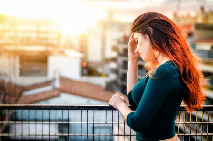 Woman with red hair on a balcony at sunset