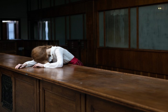 Woman resting head on wooden table in room
