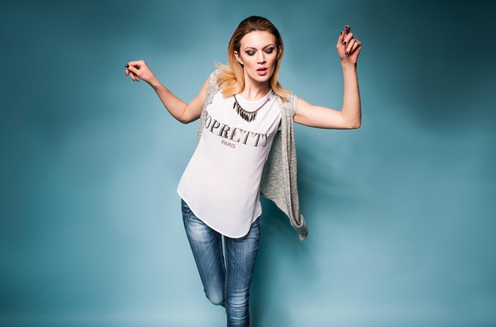 Woman in jeans and t-shirt posing against blue background