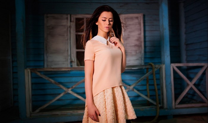 Woman in peach dress standing on a blue porch