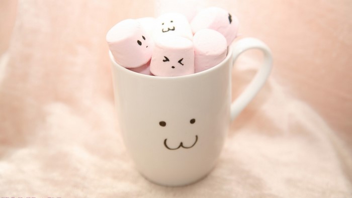 Pink marshmallows with faces in a mug
