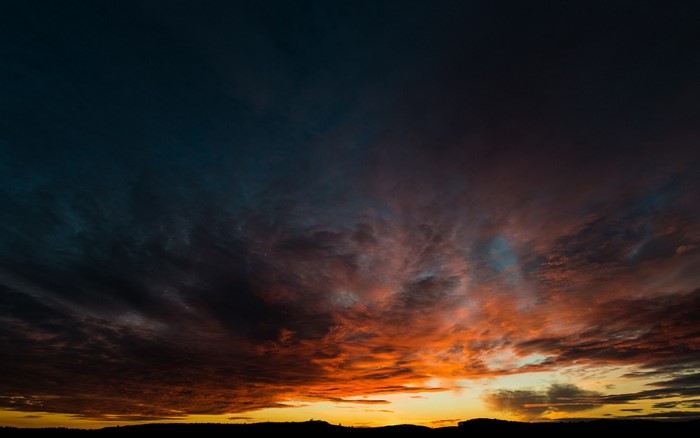 Sunset clouds over a silhouetted horizon