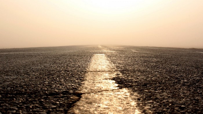 Road disappearing into a hazy horizon at sunrise or sunset
