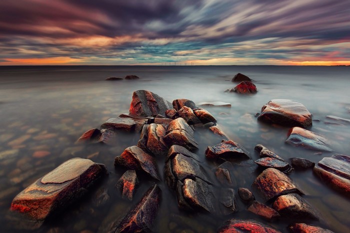 Rocky shore at sunset with colorful clouds over the ocean