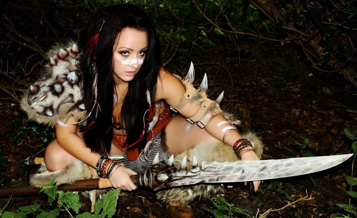 Woman in fantasy warrior costume with sword in forest