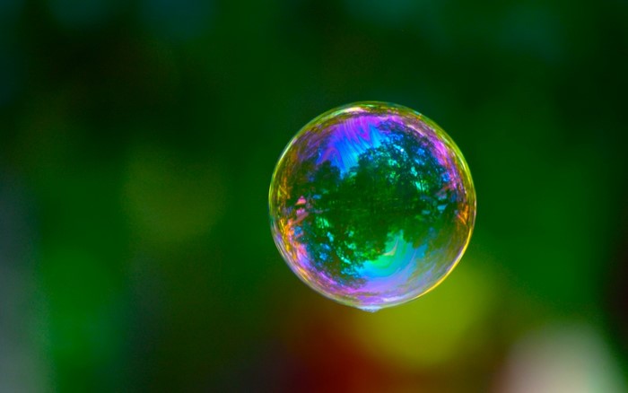 Close-up of a colorful bubble reflecting trees