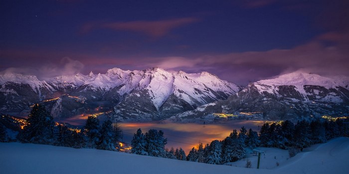 Snowy mountains at dusk with village lights
