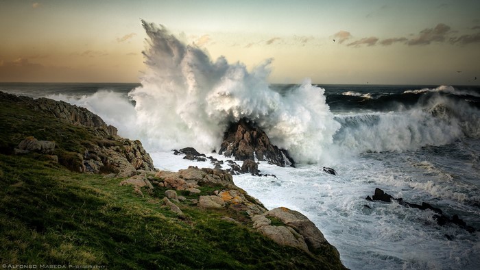 Massive wave crashing against rocks on a rocky shore