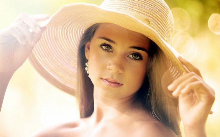 Woman in a wide-brimmed hat with pearl earrings
