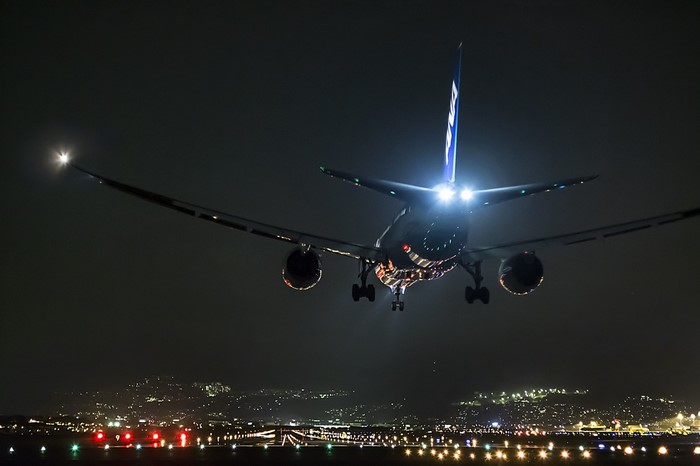Airplane landing at night with city lights on runway