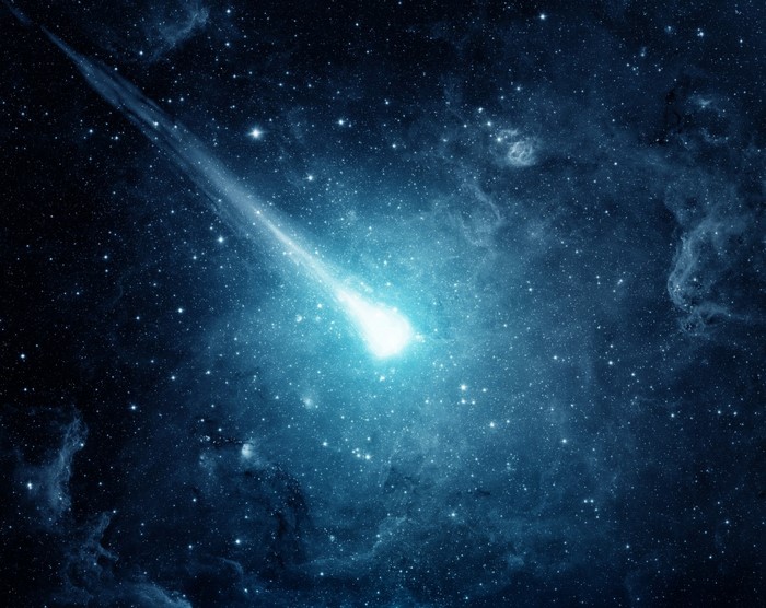 A meteor streaks across a starry nebula in outer space