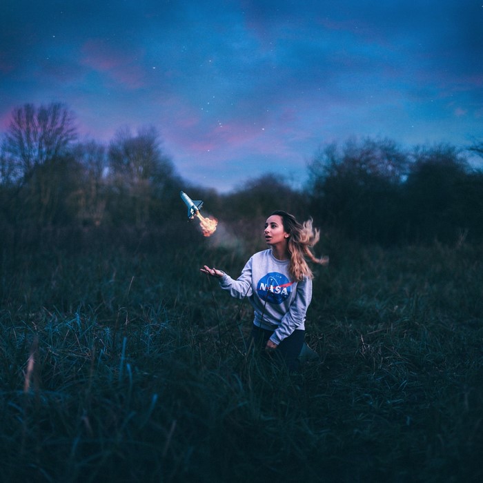 Woman with NASA sweatshirt launching a toy rocket