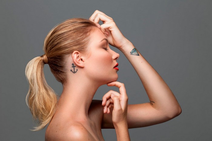 Woman with anchor tattoo behind ear and diamond tattoo on wrist