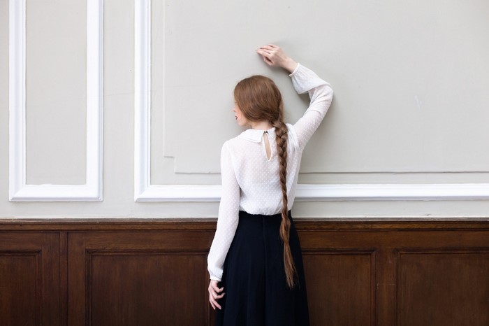 Woman with long braid leaning against wall