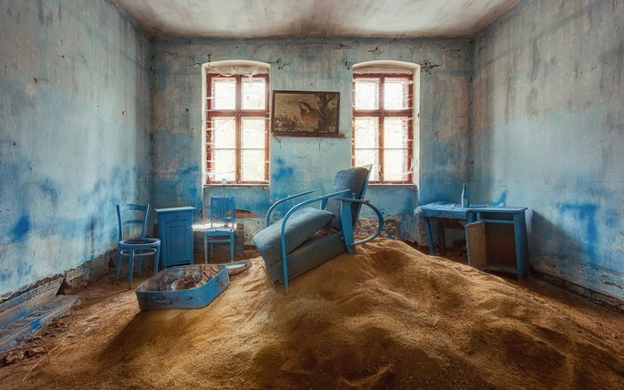 Abandoned room with sand and blue furniture