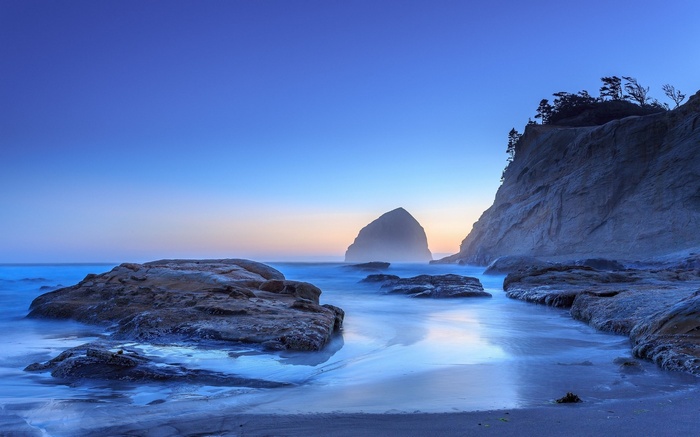 Ocean waves crashing on rocky shore at dusk