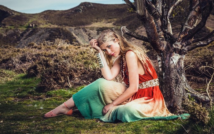 Woman in a colorful dress sitting by a tree