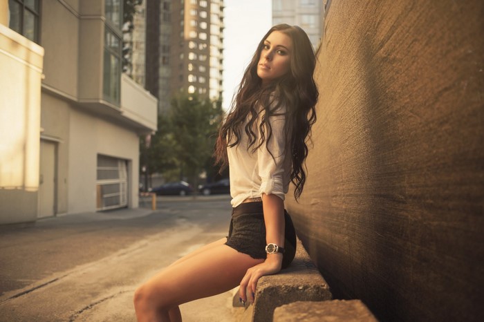 Woman sitting on a concrete ledge in an alley