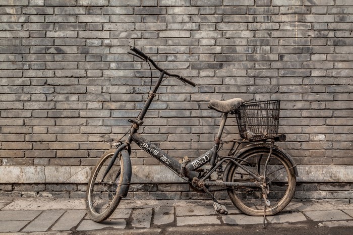 Old bicycle leaning against a brick wall