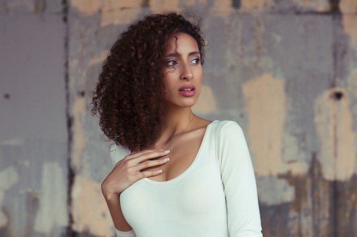 Woman with curly brown hair wearing a white top