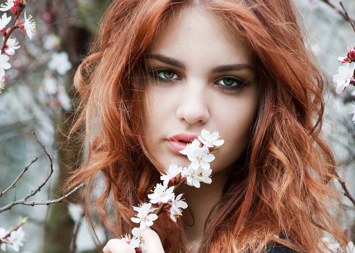Woman with red hair holding white flowers near face