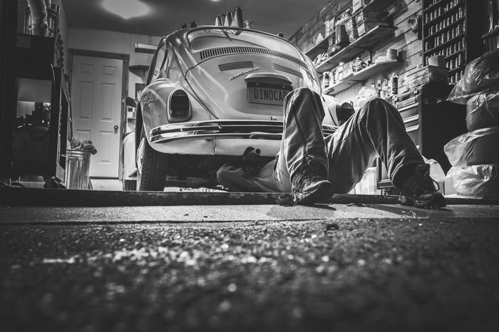 Man working on a vintage Volkswagen Beetle in a garage