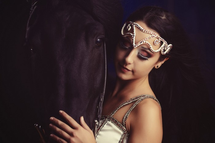 Woman with a black horse and ornate headpiece